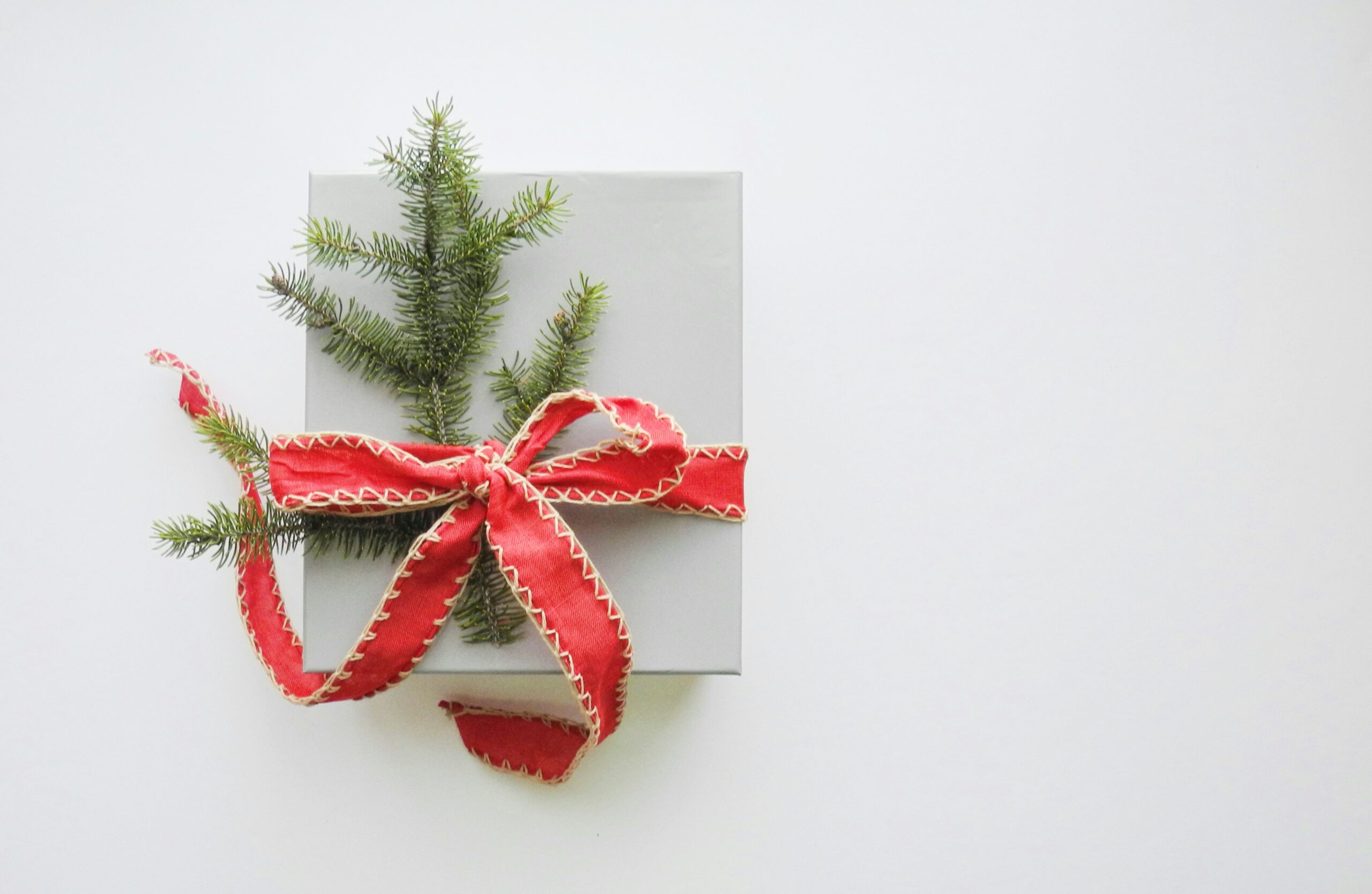 Duurzame kerstpakketten voorbeeld: eenvoudige verpakking met rood lint en dennentakje als versiering