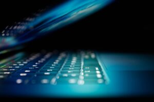 Close-up van een verlicht laptoptoetsenbord in blauw licht met halfgesloten scherm