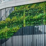 Duurzaam bedrijfspand met zonnepanelen en een groen bedekte muur als voorbeeld van verduurzamen.