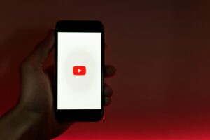 Telefoon met YouTube logo als voorbeeld van hoe je een YouTube kanaal maakt.