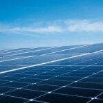 Blauwgekleurde zonnepanelen op een dak in het daglicht.
