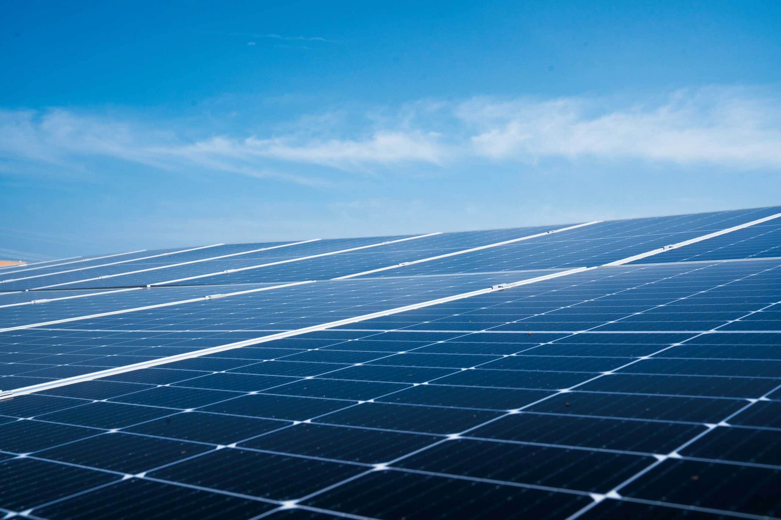 Blauwgekleurde zonnepanelen op een dak in het daglicht.